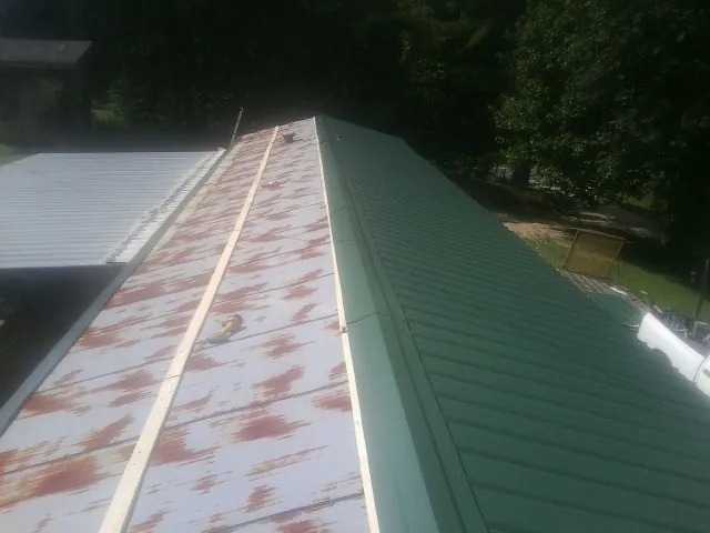 Old rusted panels beside newly installed green metal roofing — Wind Damage Roof Repair by Roofing Brothers in Southgate