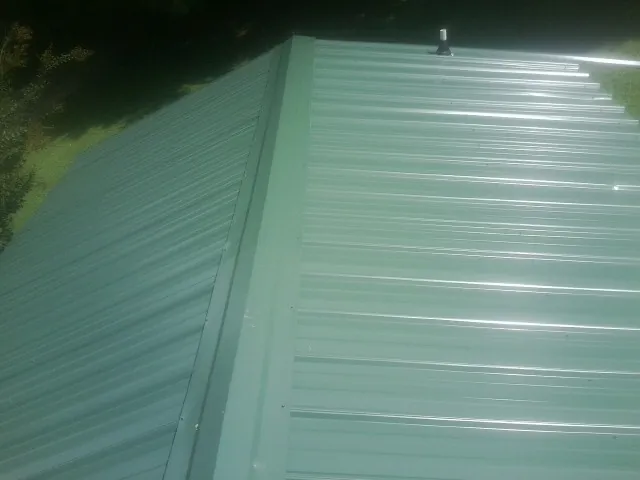 New green metal panels meeting at the ridge of a roof — Flat Roof Repair work by our crew in Southgate