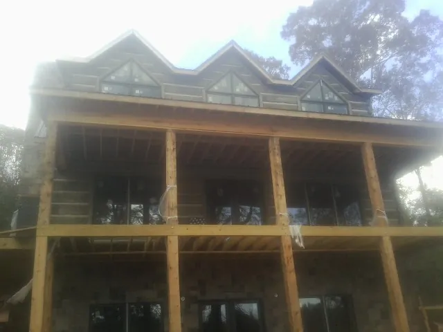 Dormers and porch framing on a large log home under construction — Roof Coating work by our crew in Southgate