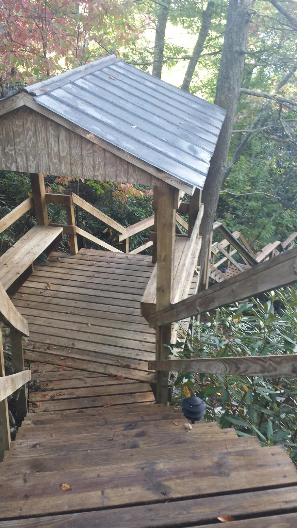 Metal roofed shelter over wooden steps on a wooded walkway — Skylight Repair & Installation work by our crew in Southgate