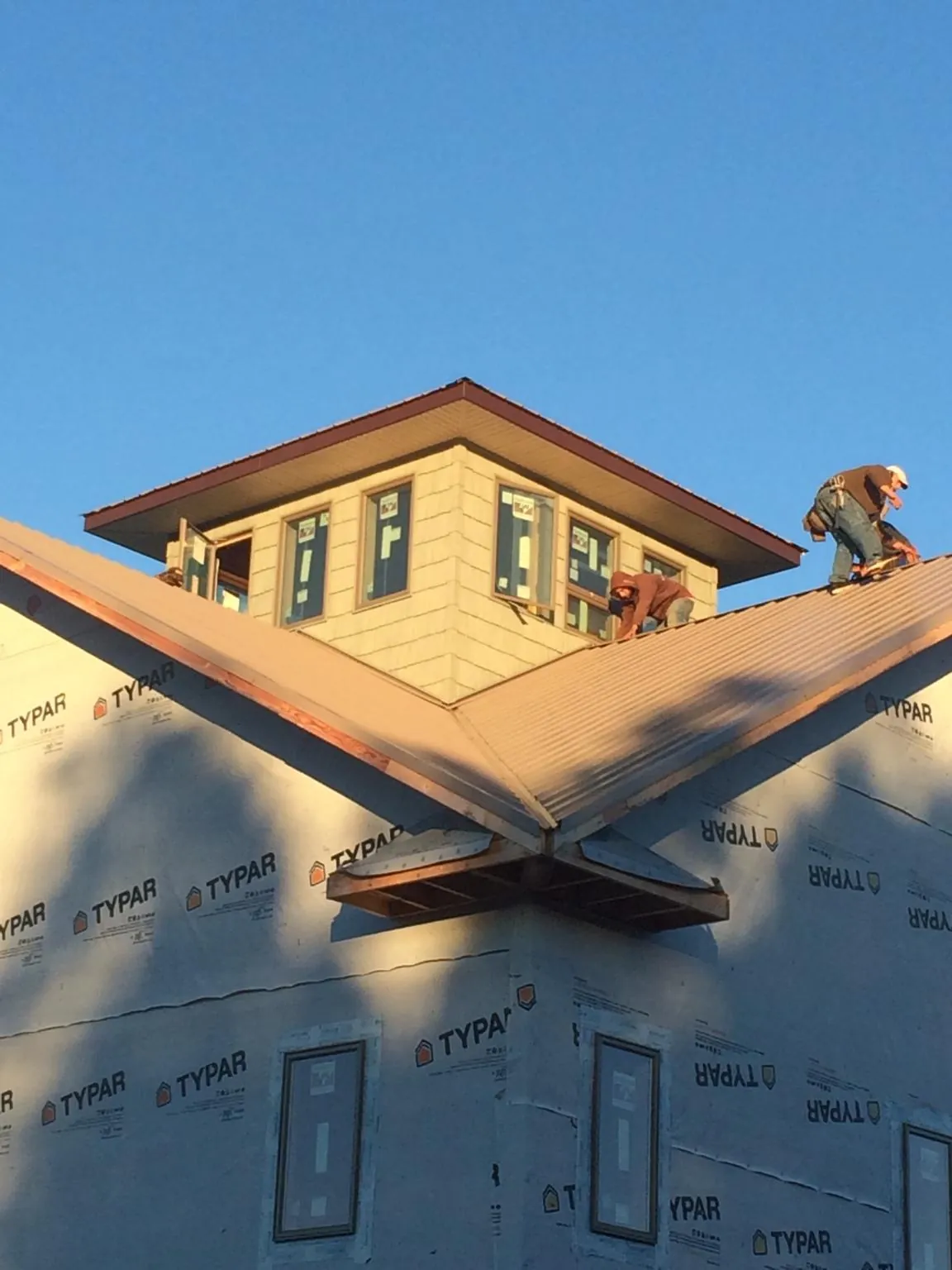 Roofers working around a rooftop cupola on a new metal roof at sunset — Roof Waterproofing in Southgate by Roofing Brothers